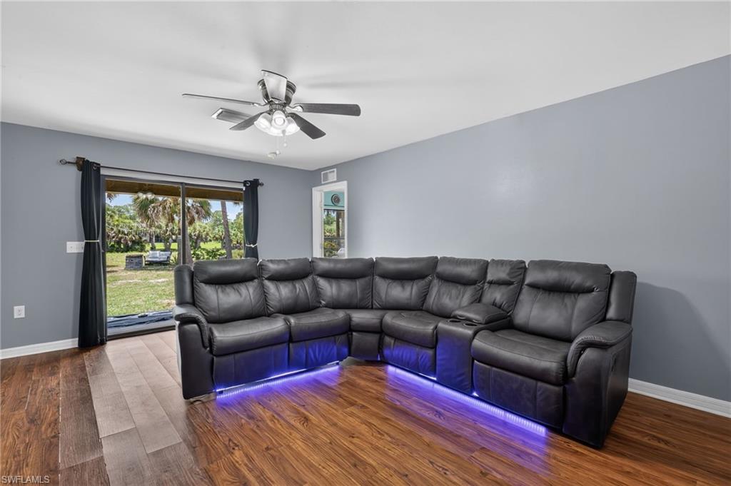 Living area featuring wood-finish flooring, light gray wall paint, and a ceiling fan with integrated lighting