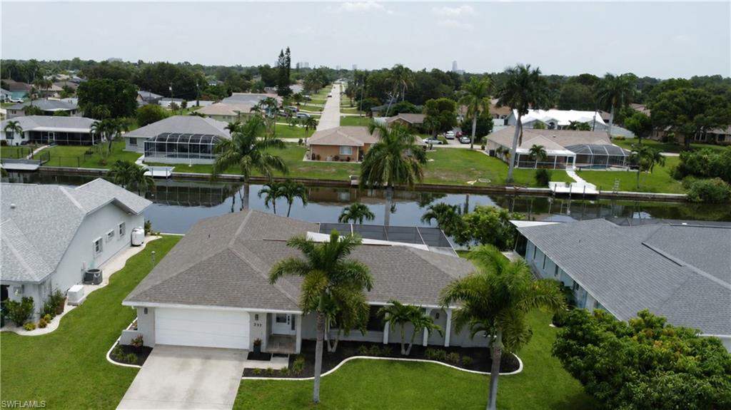 Single-story residence featuring a two-car garage, mature palm trees, and manicured landscaping