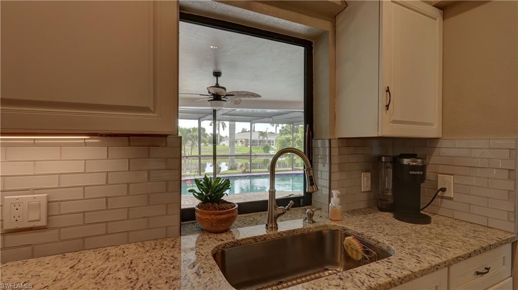 Kitchen sink featuring a gooseneck faucet, granite countertops, and a subway tile backsplash