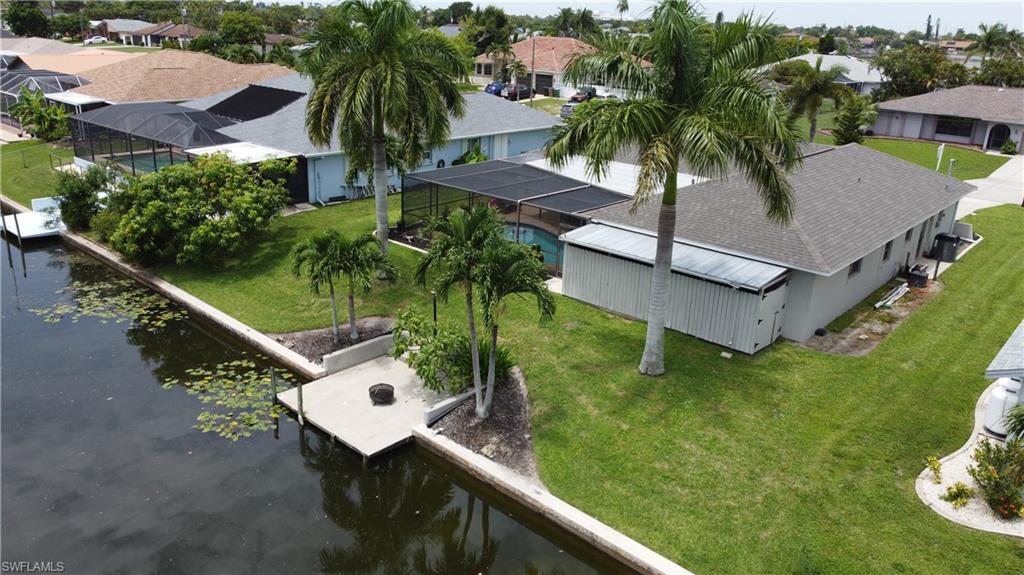 Waterfront property featuring a private boat dock, concrete seawall, and a screened swimming pool enclosure