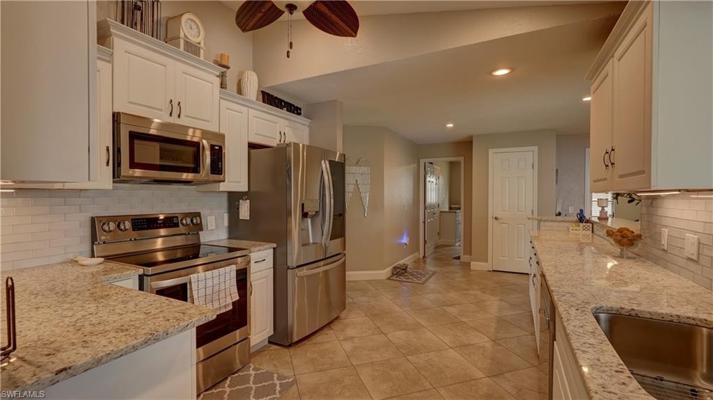 Kitchen featuring light-toned cabinetry, stainless steel appliances, granite-style countertops, and a subway tile backsplash