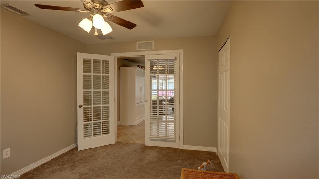 Interior room featuring a ceiling fan with light kit, neutral tone walls, and plush carpeting