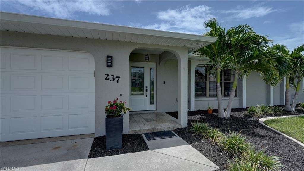 Stucco exterior featuring a two-car garage, double-door entry, and a covered entryway