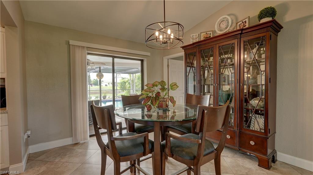 Dining area with vaulted ceilings, contemporary ceiling light fixture, and large sliding glass doors opening to an outdoor screened patio and pool area