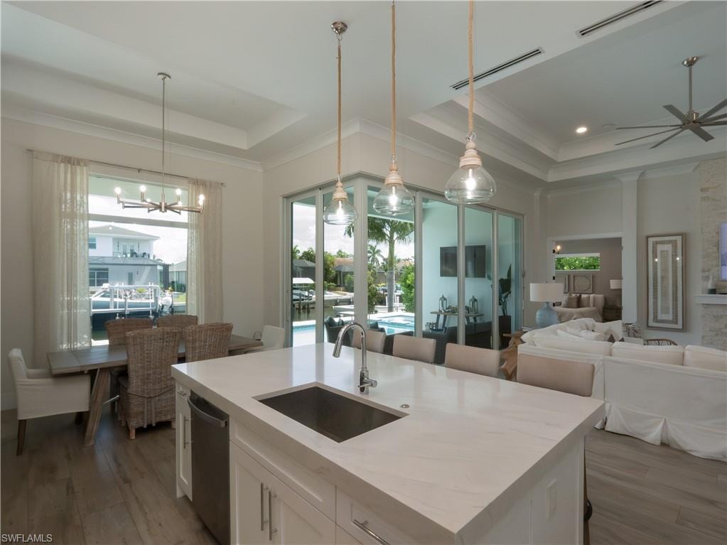 Expansive island kitchen with a stainless steel sink, integrated dishwasher, and pendant lighting