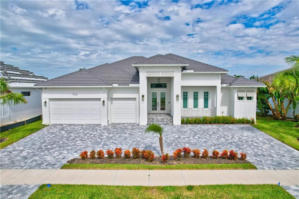 Modern architectural home featuring a distinctive peaked roofline with charcoal gray shingles, crisp white exterior, and green accent doors