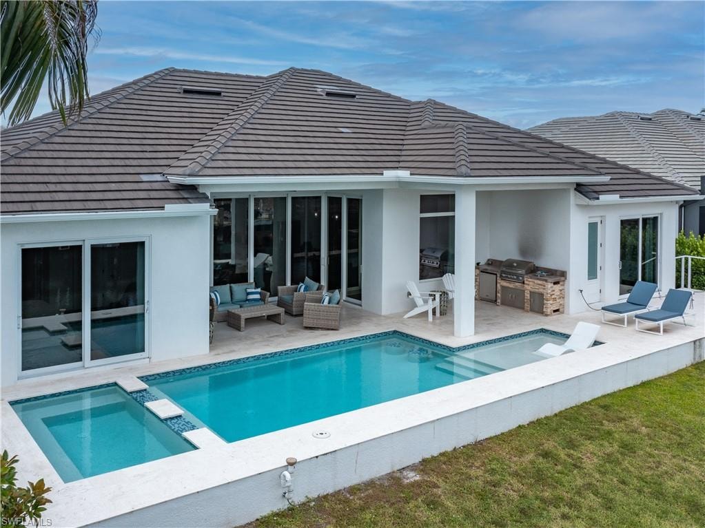 Modern residence featuring a resort-style saltwater pool with integrated spa, expansive covered lanai with multiple glass sliding doors, slate-tile roofing, manicured lawn, and a sophisticated outdoor entertaining space with built-in seating areas