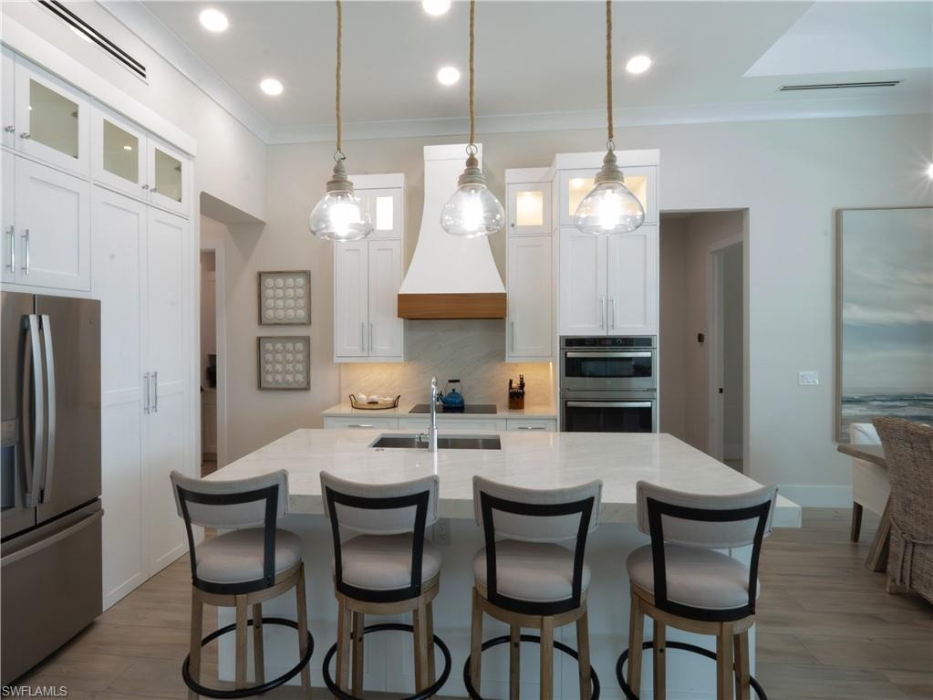 Contemporary kitchen featuring white cabinetry, stainless steel appliances, quartz countertops, and a center island with seating
