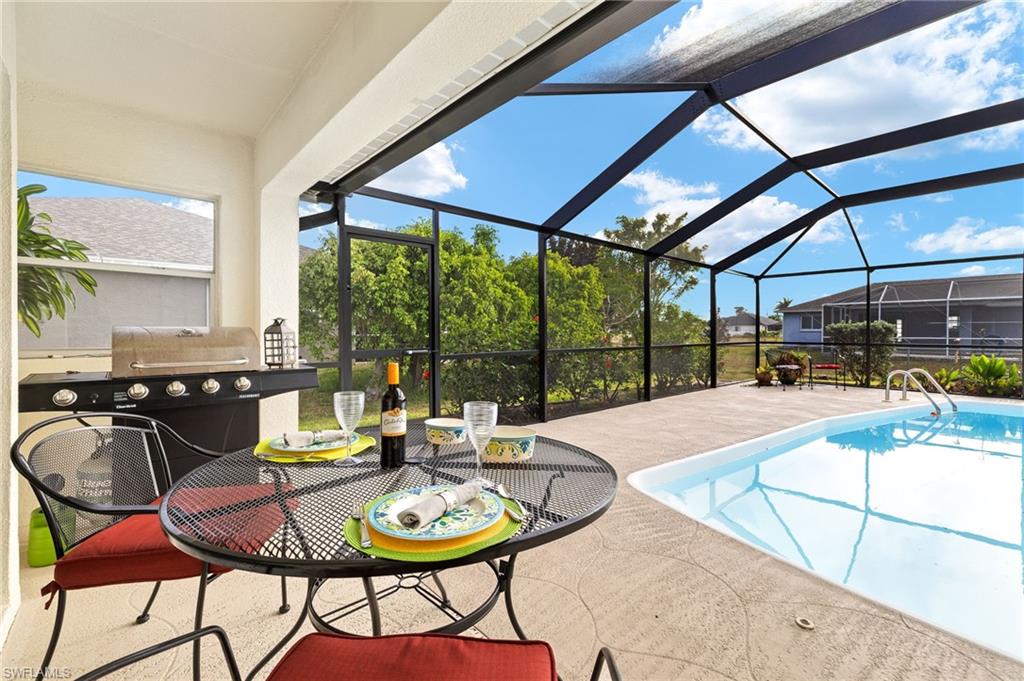 Outdoor pool with glass enclosure, a sunroom, a patio area, and grilling area