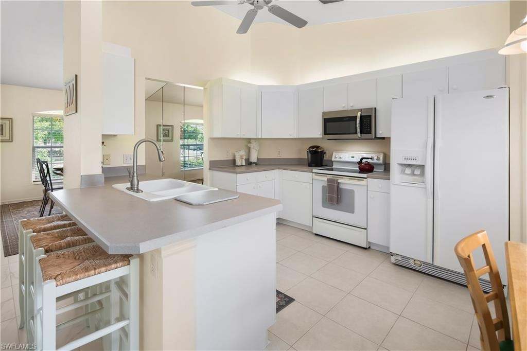 Kitchen featuring white cabinetry, light-toned countertops, and a white tiled floor