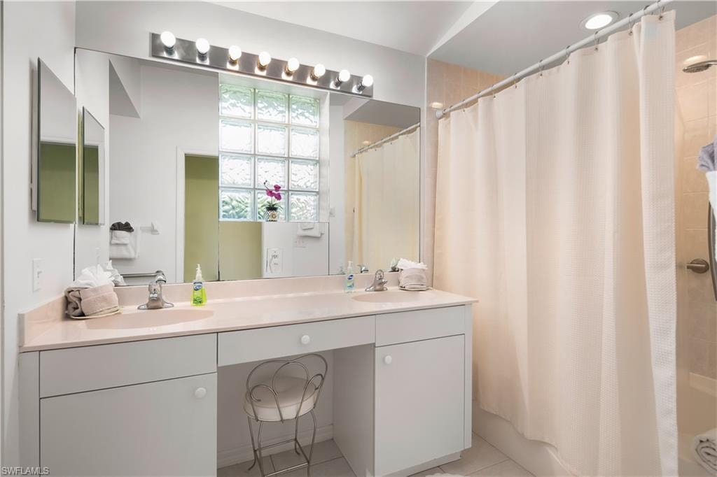 Bathroom featuring a double vanity with integrated sinks, a built-in makeup area, and a large wall mirror