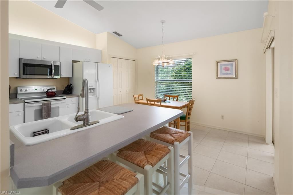 Kitchen featuring an island with breakfast bar seating, double basin sink, and pendant lighting