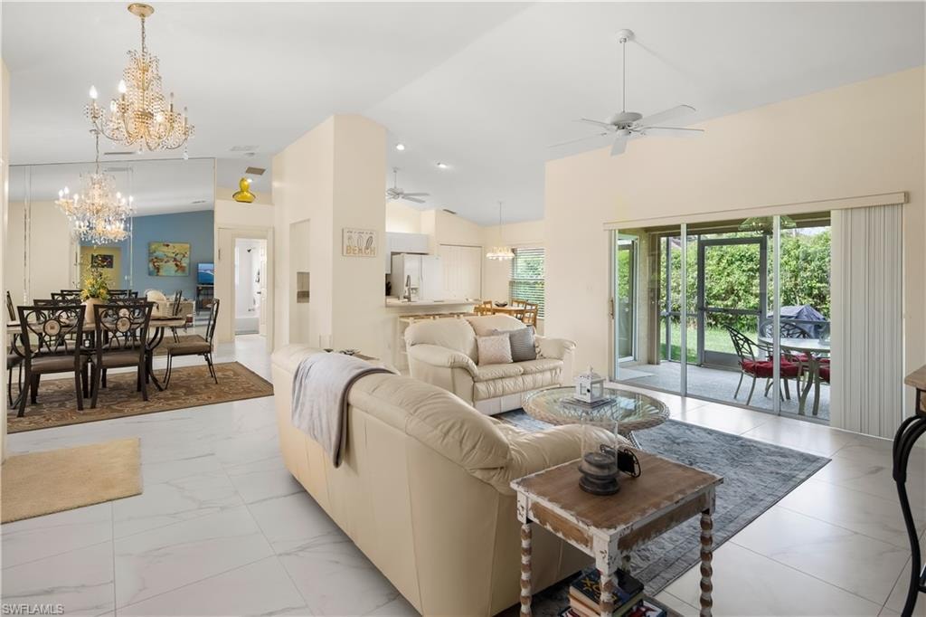 Spacious open-concept living area featuring white tile flooring and vaulted ceilings
