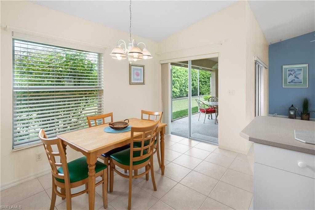 Open dining area featuring tile flooring, a large window with horizontal blinds, and direct access to an enclosed patio through sliding glass doors
