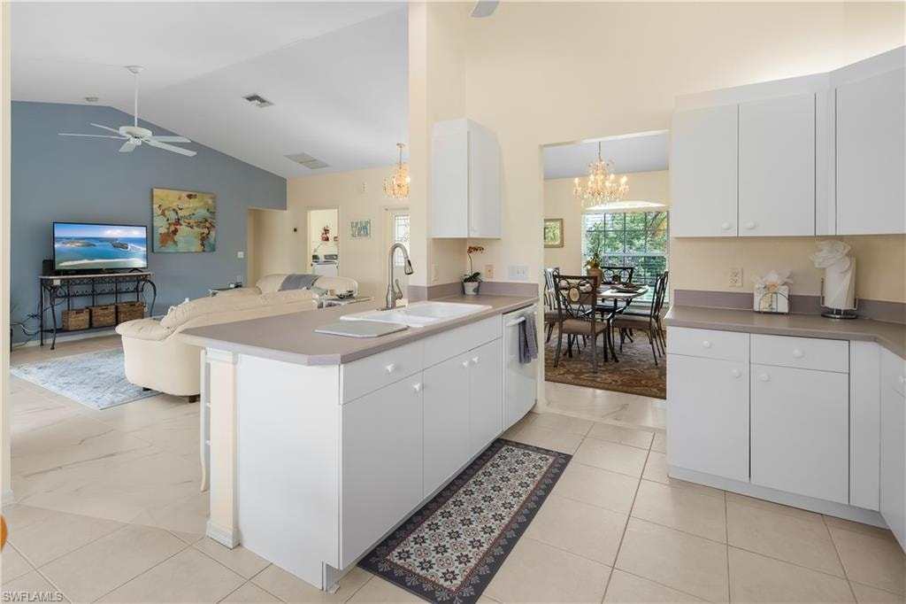 Kitchen featuring an island with double sink, white cabinetry, and light-toned countertops