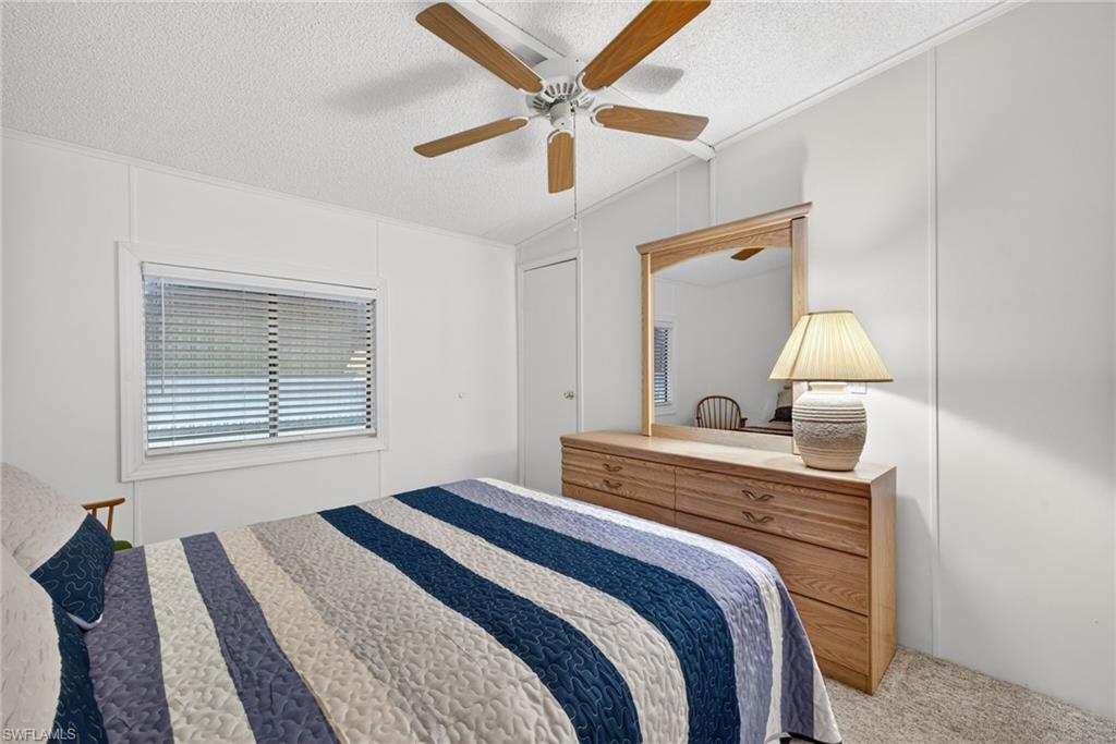 Bedroom featuring textured ceiling, light-toned wall panels, and neutral carpet flooring