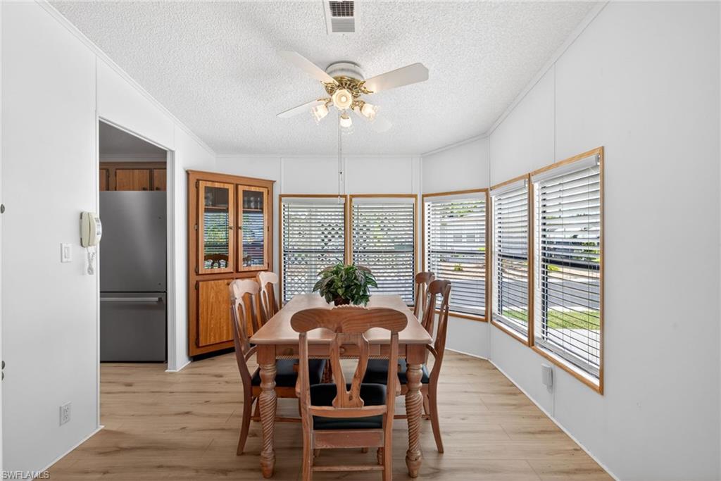 Dining area with light wood-finish flooring and multiple windows featuring blinds