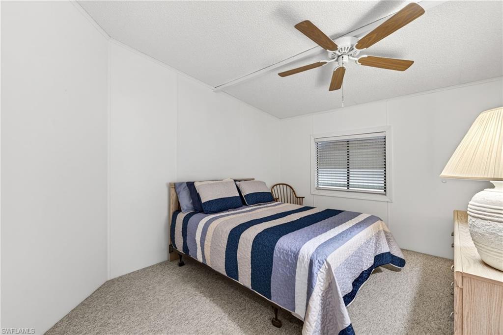 Bedroom featuring wood-finish ceiling fan, window with blinds, and light-colored carpeting