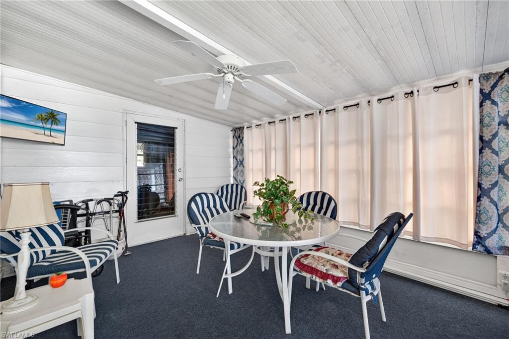 Sunroom featuring white horizontal paneling, a white paneled ceiling, and dark carpet flooring