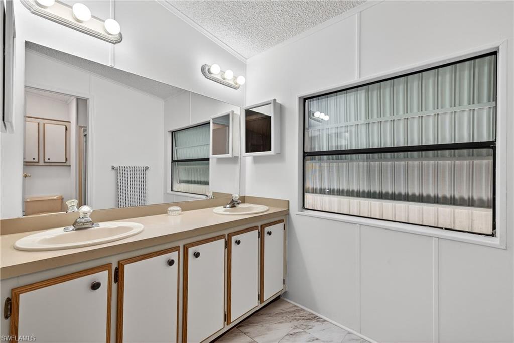 Bathroom vanity featuring dual oval sinks, a large wall-mounted mirror, and overhead strip lighting