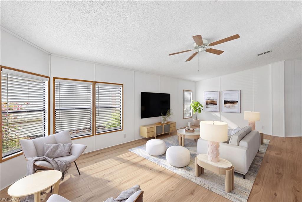 Virtually Staged Spacious room featuring wood-finish flooring, white walls, and multiple windows with blinds