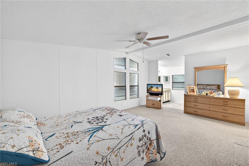Carpeted room with a ceiling fan, white wall paneling, and multiple windows