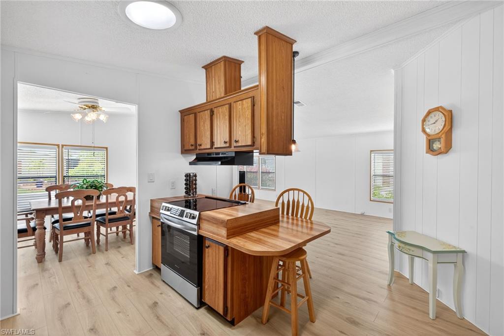 Kitchen featuring wood-finish cabinetry, stainless steel range, and light wood-finish flooring
