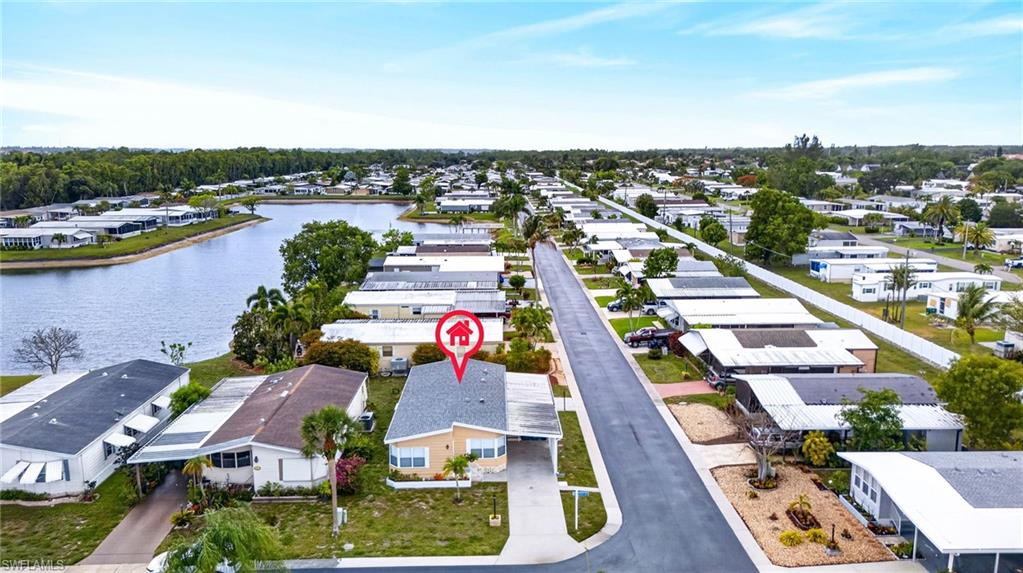 Waterfront property featuring a paved driveway, mature trees, and a spacious front yard