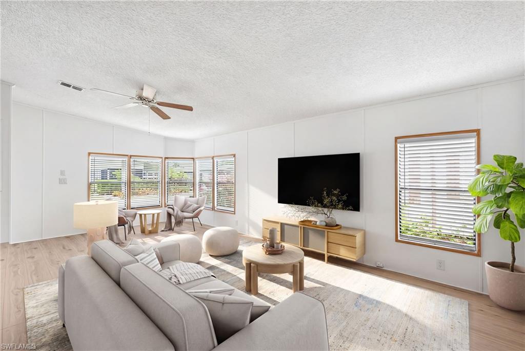 Virtually Staged Living area featuring wood-finish flooring, a ceiling fan with light fixture, and white wall paneling