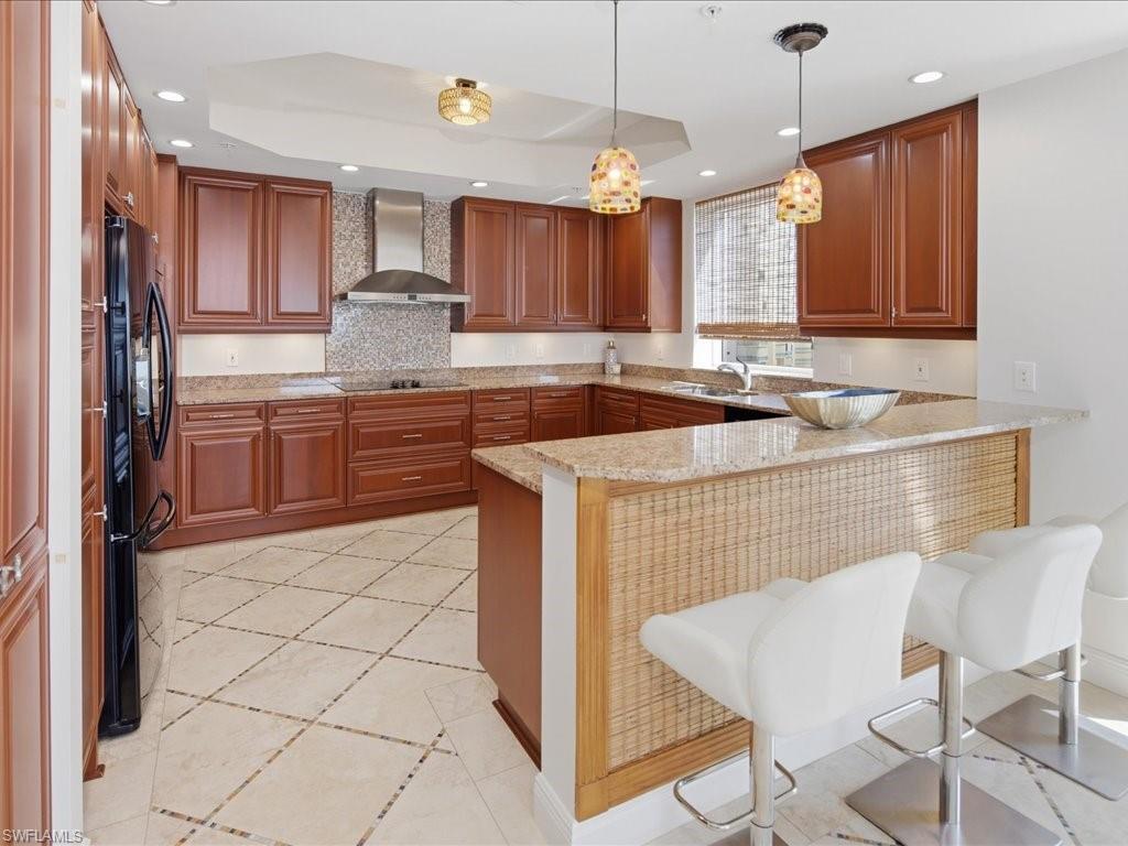 Kitchen featuring extensive wood cabinetry, granite countertops, and a full suite of black appliances
