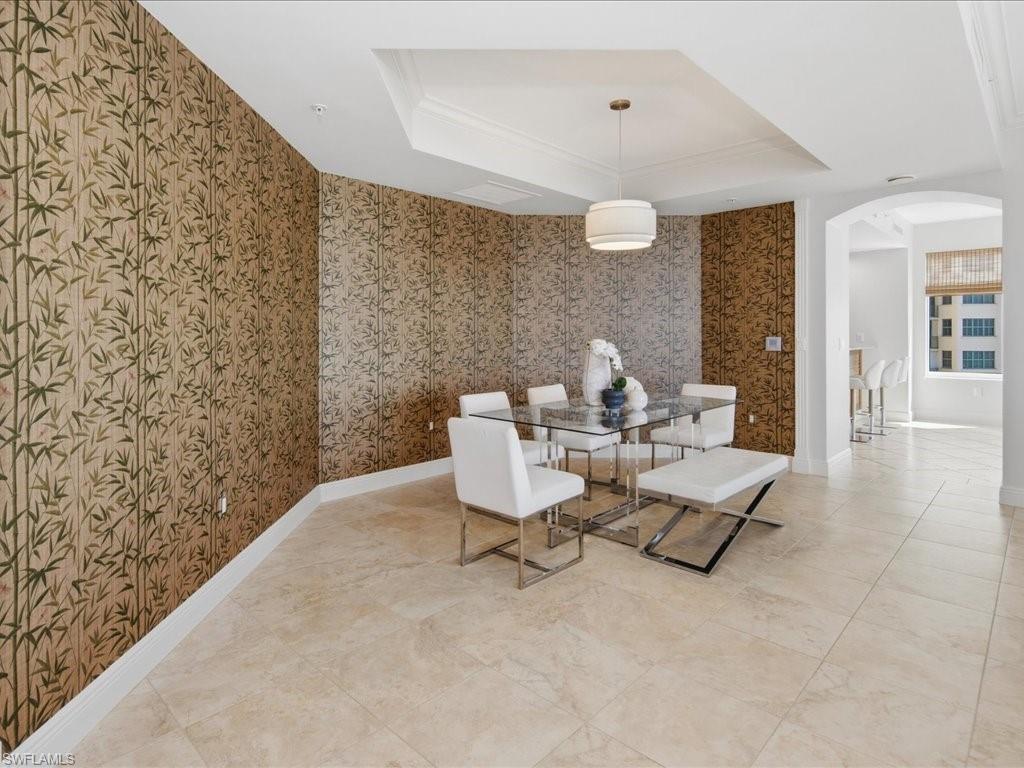 Office/3rd bedroom pacious room with large format stone tile flooring, a full wall of built-in wood cabinetry and shelving, a decorative ceiling fan, and sliding glass doors opening to a balcony