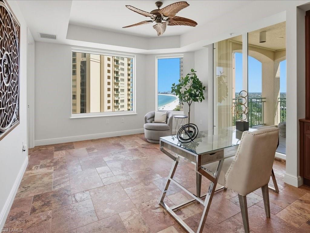 Spacious room featuring large format tile flooring, a window providing beach and water views, and direct access to a private balcony