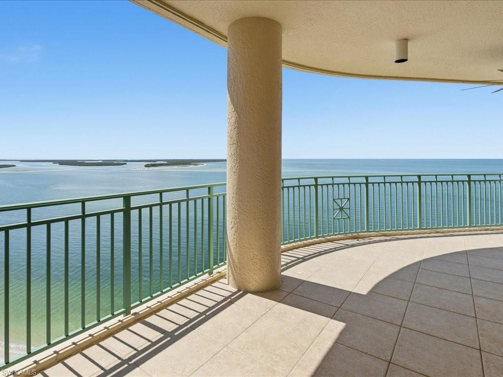Expansive curved balcony featuring a light-toned tile floor and a green metal railing