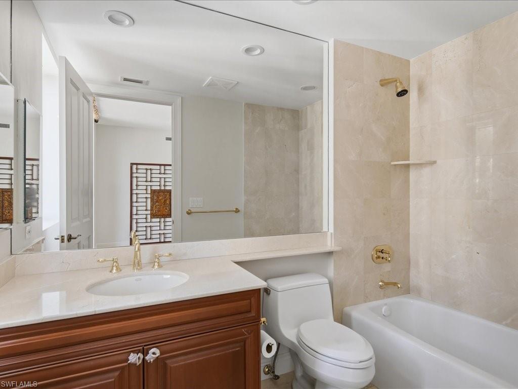Bathroom featuring a dark wood-finish vanity with an undermount sink, a light-toned countertop, and gold-finish fixtures