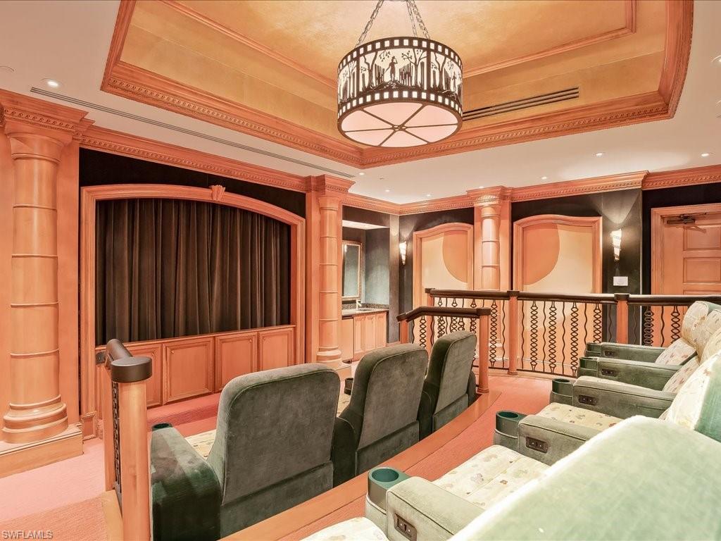 Carpeted cinema with a raised ceiling, ornamental molding, and recessed lighting
