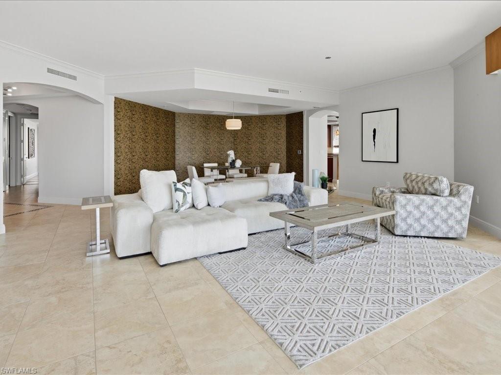 Open-concept living space featuring high ceilings, crown molding, and large format tile flooring