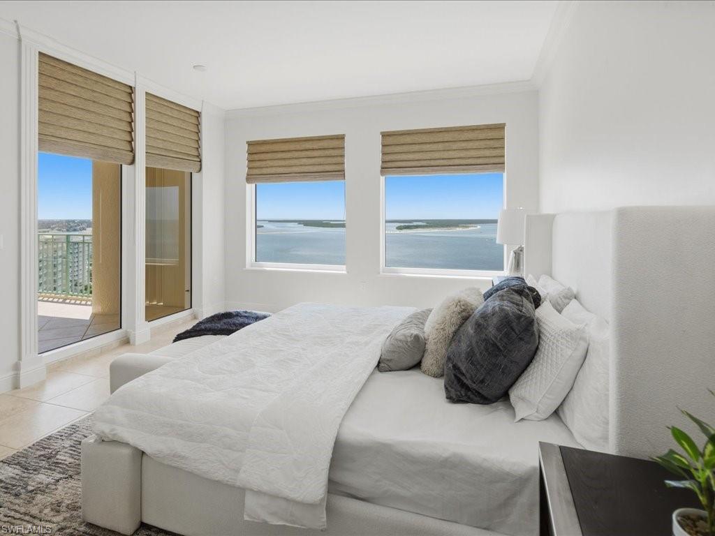 Room featuring multiple windows and a glass door with custom window treatments, offering water and distant land scenery