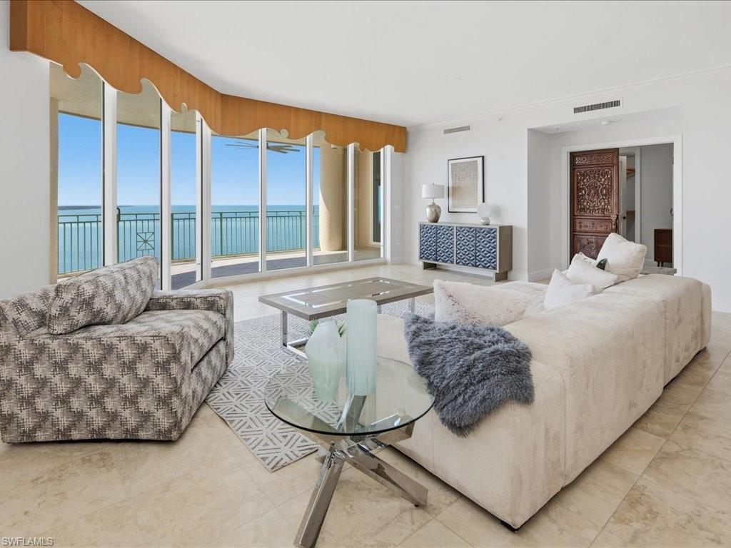 Curved wall of floor-to-ceiling windows with water scenery, complemented by light-toned tile flooring