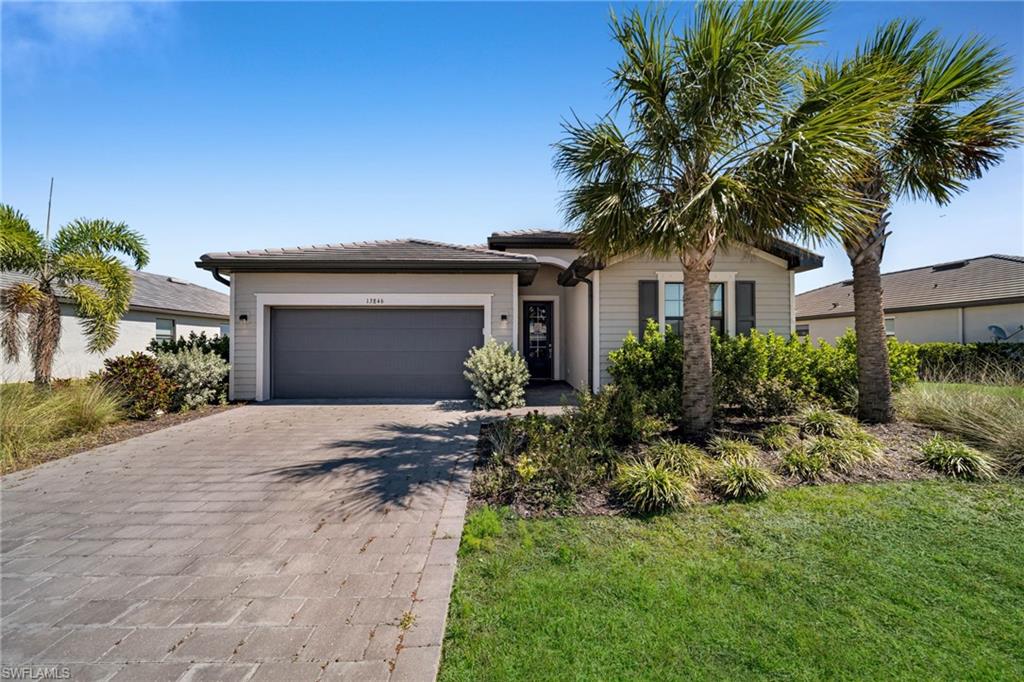 Single story home with a front yard, decorative driveway, and a garage
