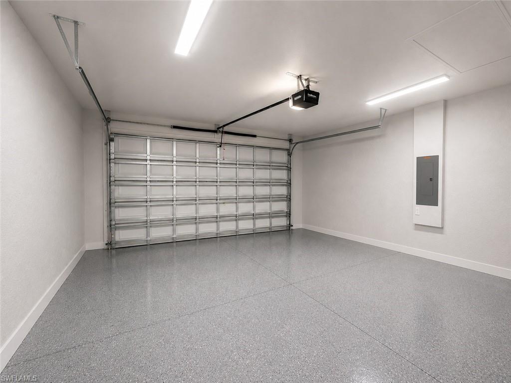 Spacious garage featuring a durable epoxy floor, a modern overhead garage door opener, and bright overhead strip lighting