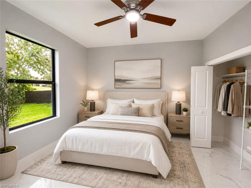 Well-lit interior space featuring expansive window, ceiling fan with integrated lighting, built-in closet with bifold door, and marble-look tile flooring
