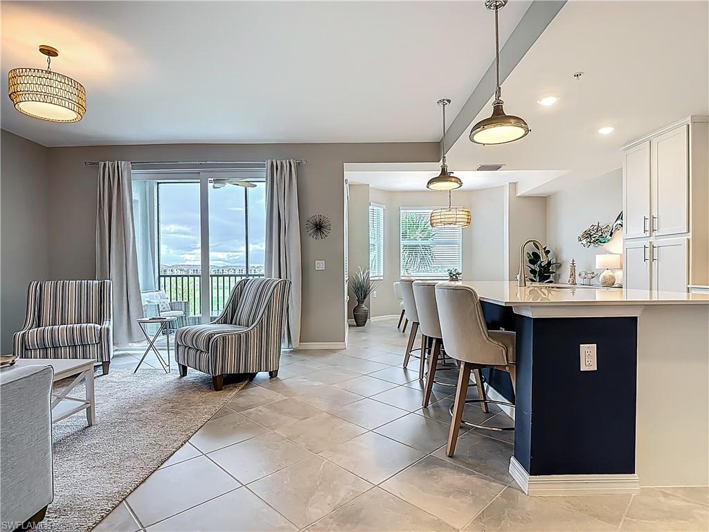 Kitchen with white cabinetry, light countertops, decorative light fixtures, a breakfast bar area, and recessed lighting