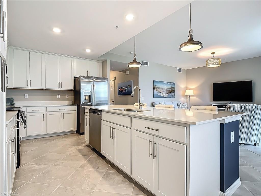 Kitchen with dishwasher, white cabinetry, light countertops, electric range oven, and an island with sink