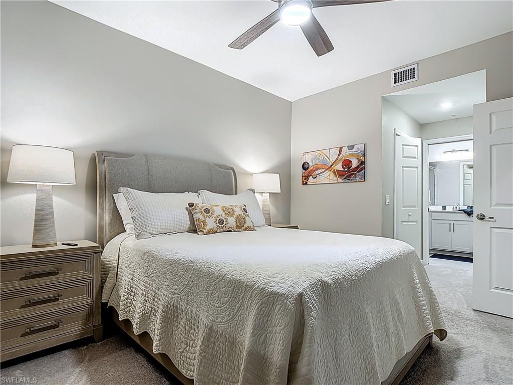 Carpeted bedroom featuring ensuite bath and ceiling fan