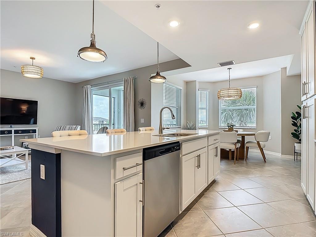 Kitchen with stainless steel dishwasher, healthy amount of natural light, light countertops, an island with sink, and recessed lighting