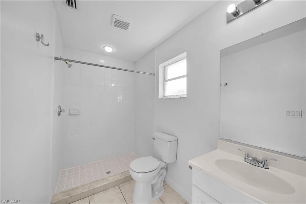 Full bathroom featuring a white tile shower, built-in vanity with integrated sink, rectangular mirror, and ceiling-mounted lighting