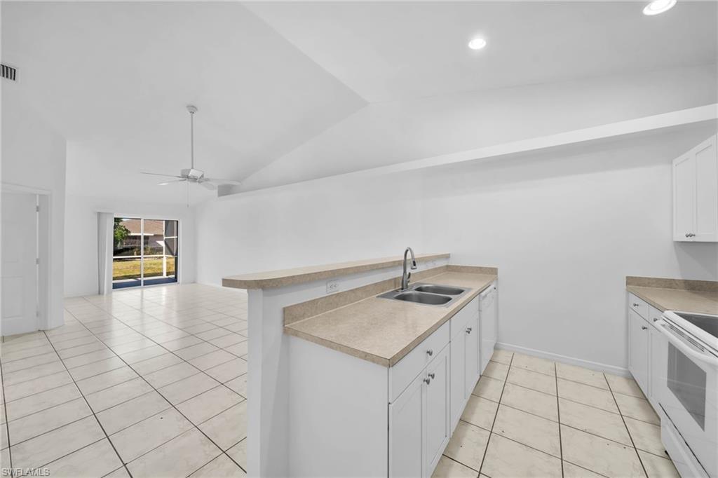 Kitchen features white cabinetry, a dual basin stainless steel sink, and light-toned countertops