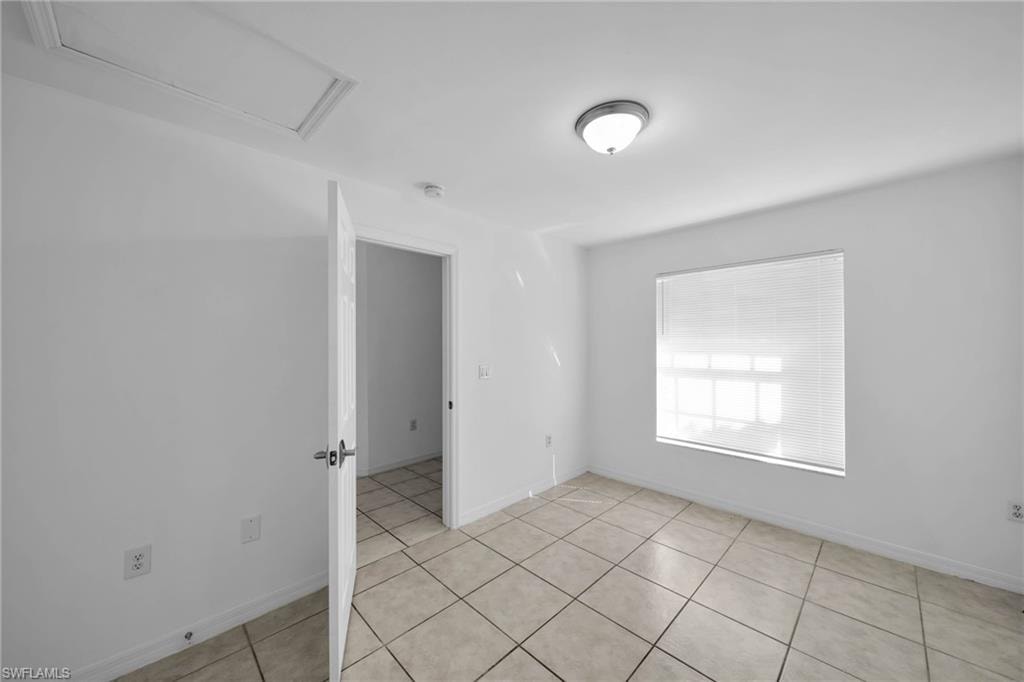 Interior room with light-colored square tile flooring and white baseboards