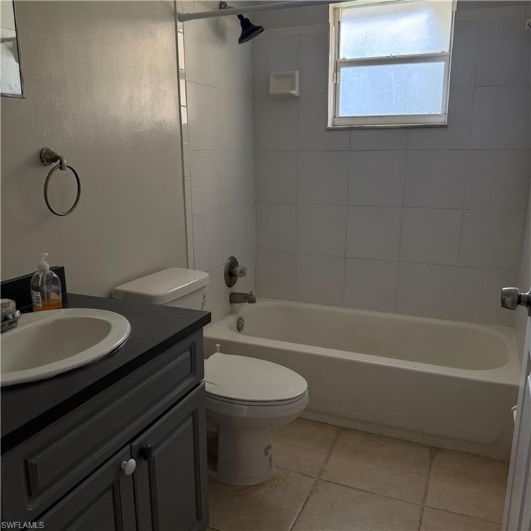 Bathroom featuring a white bathtub, tiled shower surround, and a dark grey vanity with an integrated sink