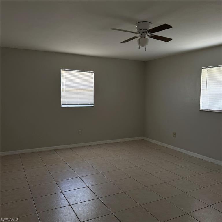 Spacious interior room featuring tile flooring, neutral wall tones, and two windows with blinds
